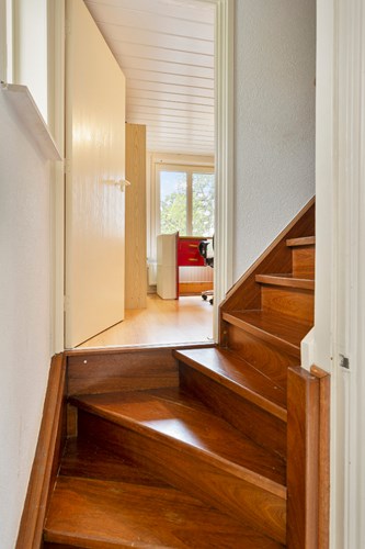 Vanuit de woonkamer met een hardhouten trap naar de opkamer, met een laminaatvloer en naar de 1e verdieping. 