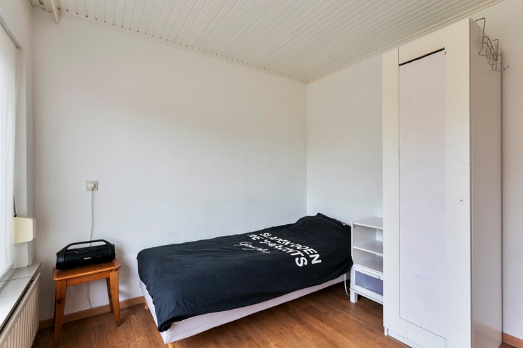 Slaapkamer gelegen aan de voorzijde, met een vinyl vloer, glasweefselbehang wanden en een licht schroten plafond. Daglicht via een hardhouten raamkozijn met dubbele beglazing en een rolluik. 