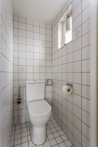 In de bijkeuken bevindt zich ook een volledig licht betegeld toilet met een stucwerk plafond met inbouwspot. Natuurlijke ventilatie middels een raampje met enkel bewerkt glas en een vliegenhor. 