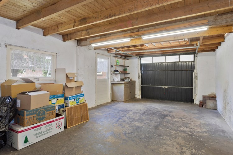 De garage is voorzien van een betonvloer, halfsteens gevels en een golfplaten dak (asbest). 