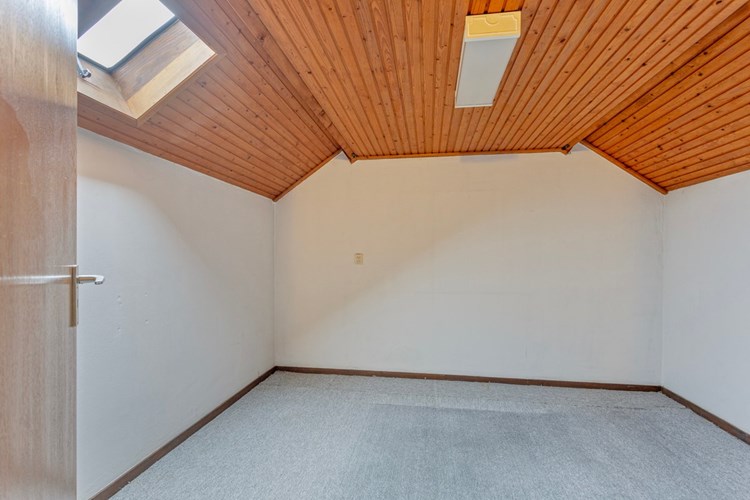 Ruime hobby-/slaapkamer met vloerbedekking, behangen wanden en een schroten plafond. Met een radiator en een dakraampje. Meer gebruiksmogelijkheden indien er een groter dakraam of een dakkapel geplaatst wordt.