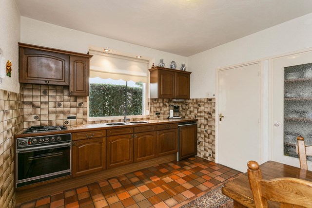 Het keukenblok is in een wandopstelling geplaatst, met rechts de deur naar de praktische, koele kelder.