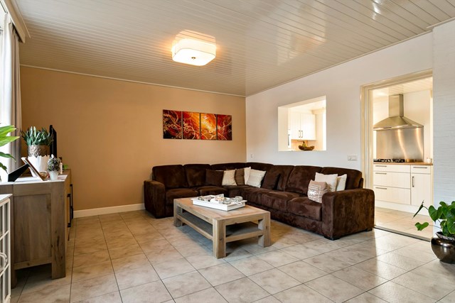 De woonkamer heeft een lichte tegelvloer met vloerverwarming en is direct met de keuken verbonden.