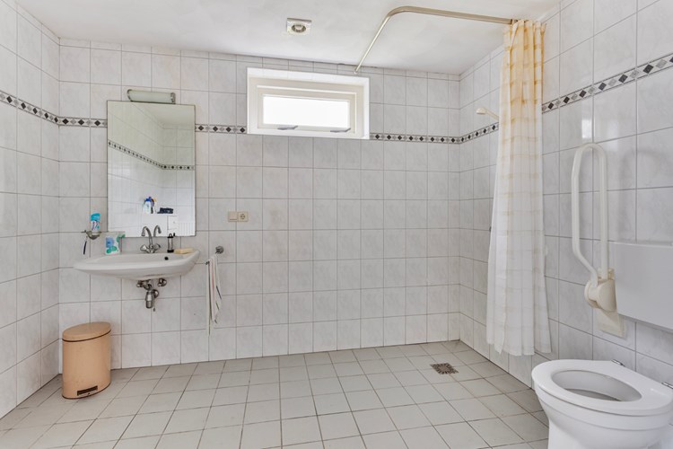 De badkamer is voorzien van een lichte anti-slip tegelvloer, volledig licht betegelde wanden en een stucwerk plafond. Met een wastafel met spiegel, mechanische ventilatie en natuurlijke ventilatie middels een hardhouten raampje met dubbele beglazing. 