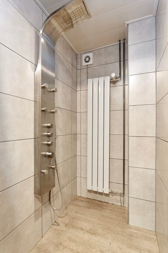 Deze separate doucheruimte is volledig betegeld met een kunststof panelen plafond met inbouwspots. Met een inloopdouche met een regendouche en zijsproeiers. Mechanische ventilatie is aanwezig. 