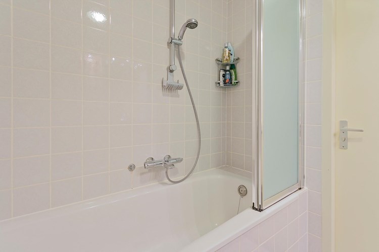 Stalen ligbad met een douchegarnituur, thermostaatkraan en een wegklapbaar spatscherm. Mechanische ventilatie is aanwezig. 