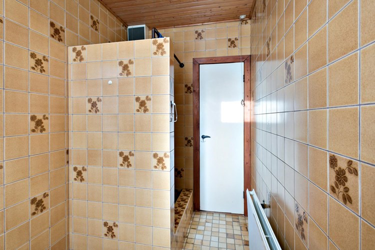 Een volledig betegelde, authenieke badkamer met een schroten plafond. Voorzien van een een douche en mechanische ventilatie. 