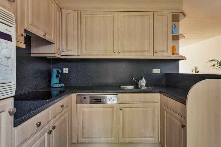 De lichte keukeninrichting is voorzien van een RVS spoelbak met restbakje, een keramische kookplaat, een afzuigkap, een koelkast, een combimagnetron en een vaatwasser.