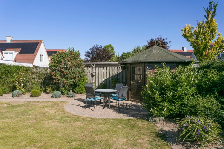 Achter in de tuin bevindt zich een houten tuinhuis met dakshingles en elektra. Voor het tuinhuis ligt ook een ruim terras. Heerlijk vrije achtertuin!