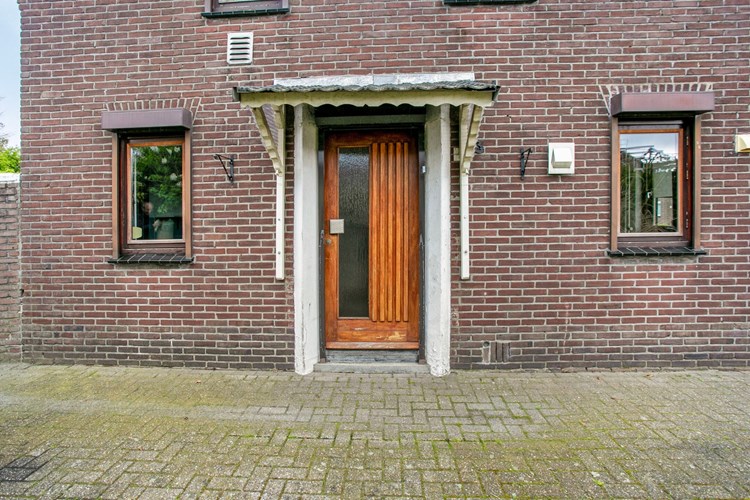 Via een hardhouten voordeur met afdakje toegang tot de woning. De voordeur is voorzien van enkel glas en een rolluik.