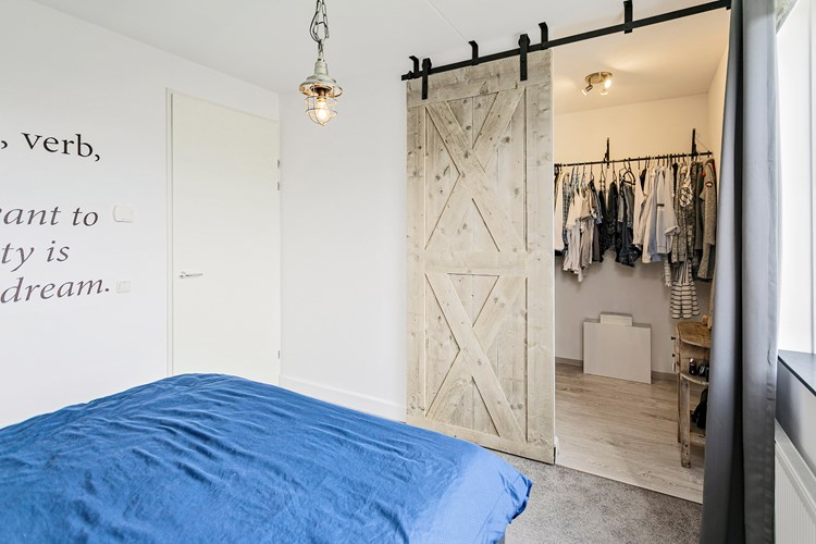 In deze slaapkamer via een fraaie schuifdeur direct toegang tot een praktische inloopkleedruimte.