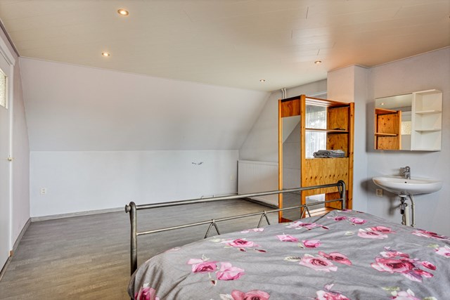 De slaapkamers zijn voorzien van een fijne laminaatvloer; rechts ziet u de wastafel en deur naar het balkon.