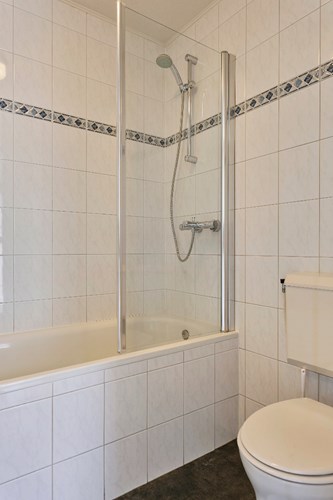 De volledig betegelde badkamer is voorzien van een ligbad met thermostaatkraan en een kunststof spatscherm en een 2e toilet.