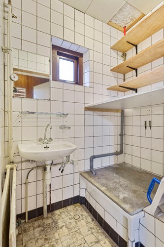 Wasruimte c.q. doucheruimte, met een tegelvloer en volledig licht betegelde wanden. Voorzien van een wastafel, een douche en de aansluitingen voor de wasapparatuur. Natuurlijke ventilatie middels een raampje. 