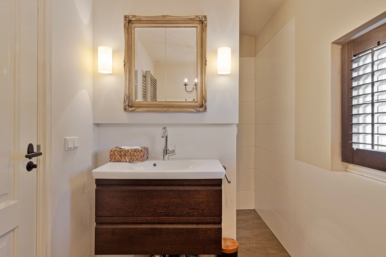 Het badmeubel met wastafel en spiegel, welke dient als opbergkast en is voorzien van een audioinstallatie t.b.v. de plafondspeakers. Daglicht via een glas-in-lood raampje (dubbel glas) en een shutter. 