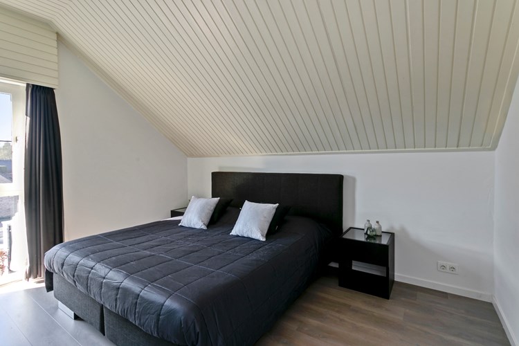 Slaapkamer, gelegen aan de achterzijde. Met een laminaatvloer, stucwerk wanden en een licht schroten plafond. Daglicht via een hardhouten kozijn (draai-/kiep) met dubbele beglazing.