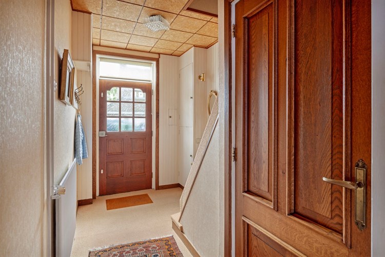 Via een hardhouten voordeur met enkel  bewerkt glas toegang tot de woning. De ruime hal is voorzien van vloerbedekking, behangen wanden en een panelen plafond. Meterkast.