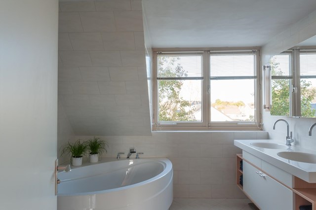 De badkamer in lichte kleurstelling beschikt over een groot ligbad in hoekopstelling en ook hier heeft u veel direct daglicht.
