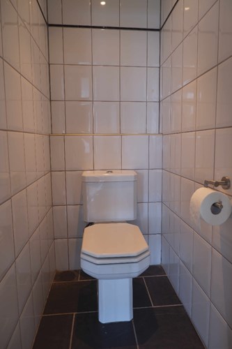 In de gang/entree ligt dit volledig betegeld toilet met een panelen plafond met inbouwspots en een duoblok. 
