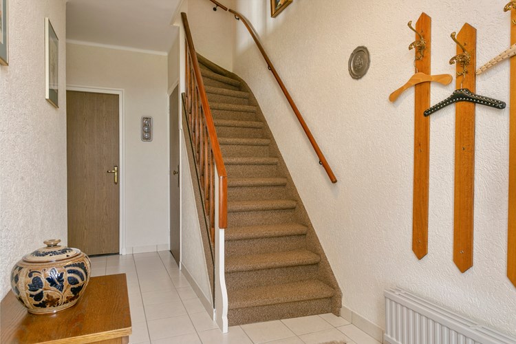 De ruime entree heeft een lichte tegelvloer, granol wanden en een stucwerk plafond. Onder de trapopgang bevindt zich een praktische bergkast. 