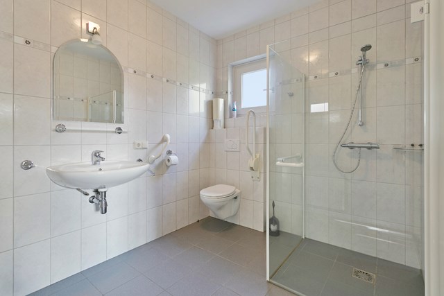 De badkamer is geheel betegeld en heeft een heel praktische inloopdouche, vrijhangend toilet en wastafel.