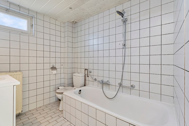 Badkamer met een lichte tegelvloer, volledig licht betegelde wanden en een MDF plafond met inbouwspots. Voorzien van een 2e toilet en een ligbad met douche mogelijkheid en een 'Grohe' thermostaatkraan.  