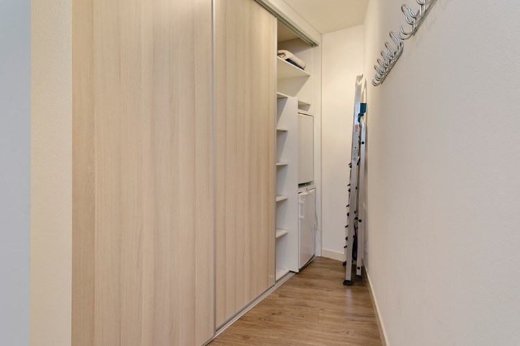 Inloopkleedruimte met een PVC-vloer, spuitwerk wanden en een spuitwerk plafond. Met een vaste kastenwand met schuifdeuren en een aansluitmogelijkheid voor een (extra) koelkast en/of diepvries. 