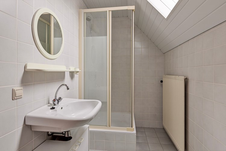 Badkamer II, met een tegelvloer, volledig licht betegelde wanden en een kunststof schroten plafond. Met een douchecabine, een wastafel en een 2e toilet. Natuurlijke ventilatie middels een Velux dakraampje met dubbele beglazing. 