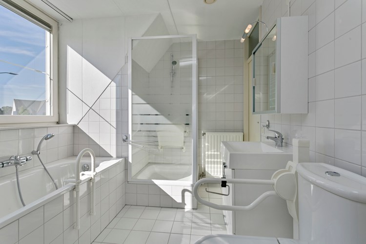 De badkamer is volledig licht betegeld met een spuitwerk plafond. Met een stalen ligbad met thermostaatkraan, een douchecabine met een thermostaatkraan en een stoeltje, een 2e toilet en een badmeubel met een vaste wastafel en een spiegelkast met verlichting. 