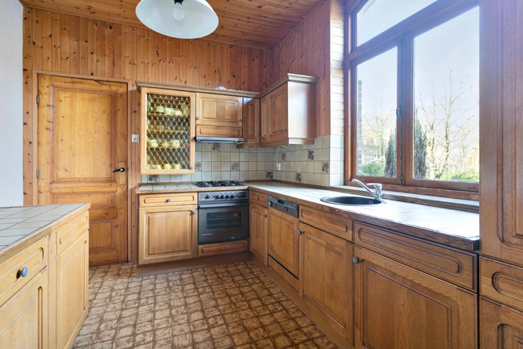 Keuken (afmeting ca. 4,00 m. x 3,00 m.) met een linoleumvloer, met eronder een authentieke tegelvloer, behangen- en schroten wanden en een schroten plafond. Eiken keukeninrichting in een hoekopstelling voorzien van een gaskookplaat, een afzuigkap, een elektrische oven, een vaatwasser en een grote koelkast met vriesgedeelte. 