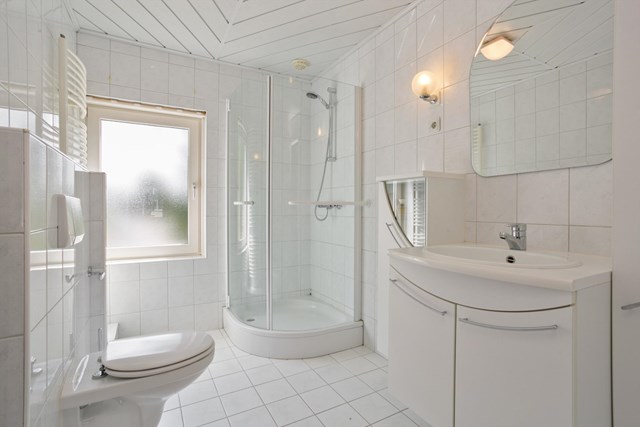 De geheel betegelde badkamer met douche, badmeubel en tweede, vrijhangend closet.