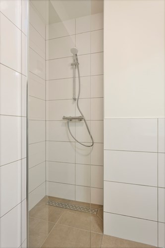 De badkamer is voorzien van volledig betegelde inloopdouche met glazen wand en een thermostaatkraan en mechanische ventilatie.