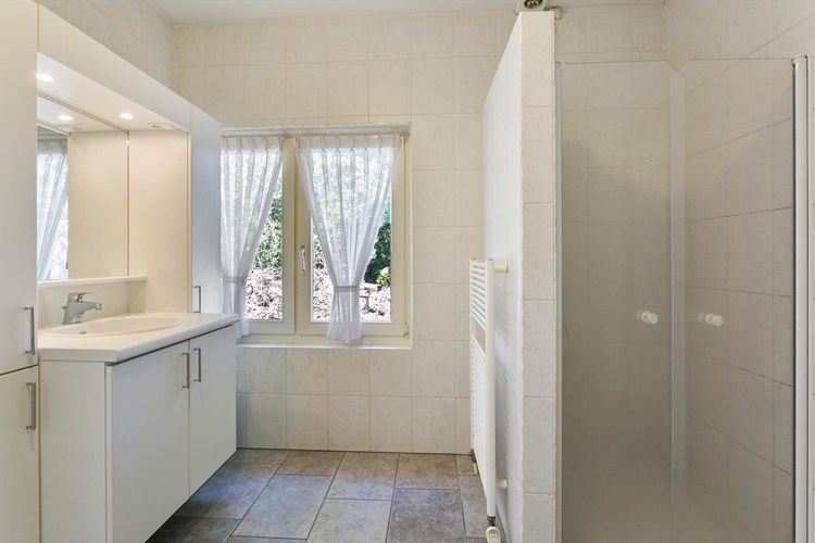 De badkamer is voorzien van een groot badmeubel met een wastafel, een grote spiegel met inbouwspots en veel kastruimte. Verder een douchecabine met een thermostaatkraan, een wandcloset met opzetplateau en een kunststof ligbad.